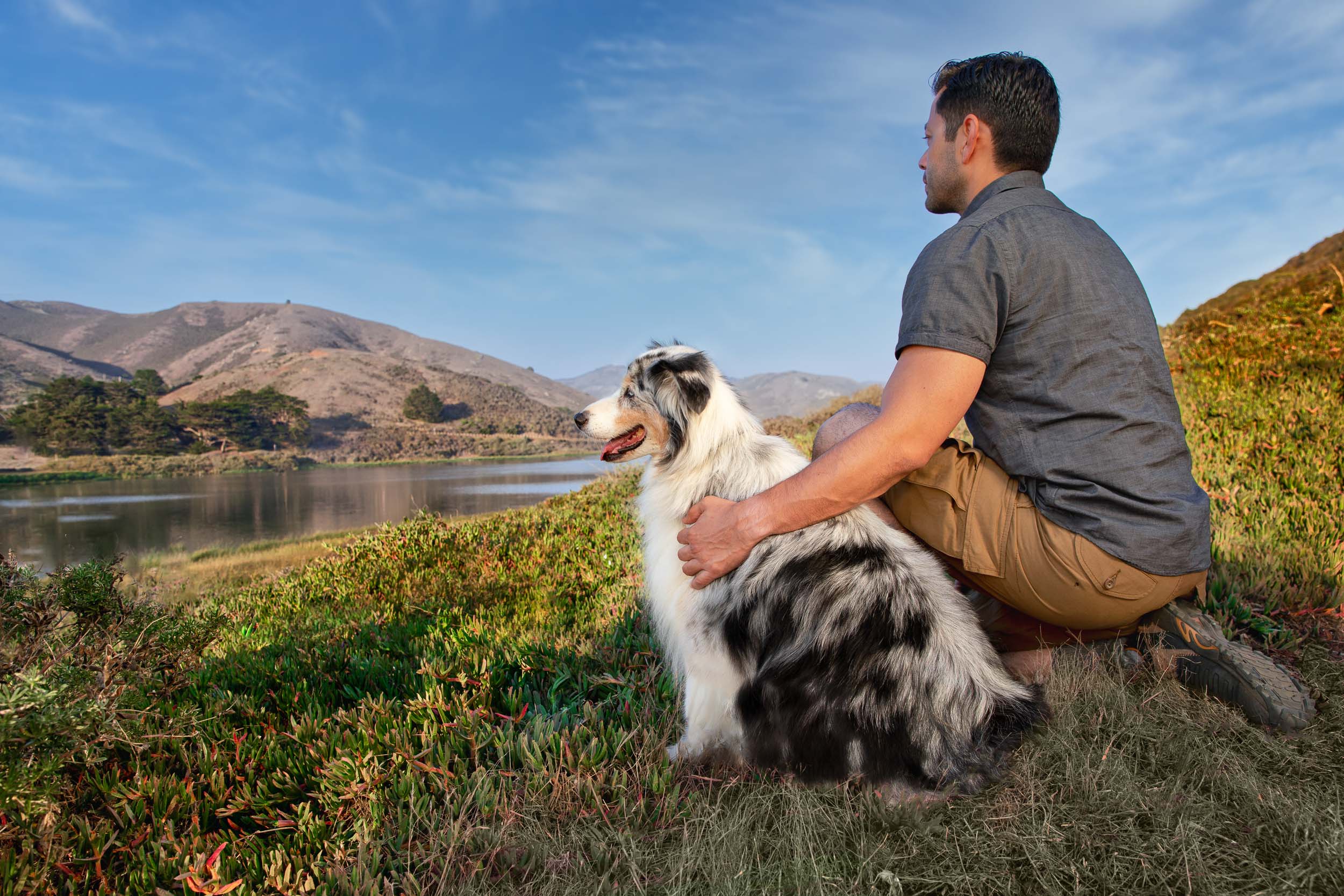 Pet and People Photography | Man Kneeling Next to Dog Near Lake