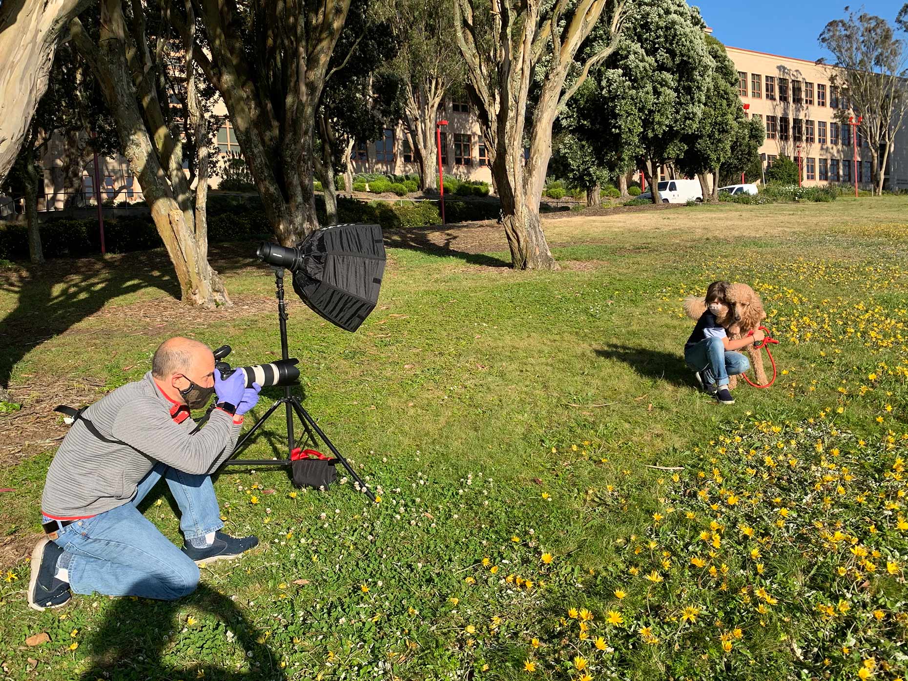 behind the scenes shot of photographer mark rogers working with girl and poodle while wearing a mask